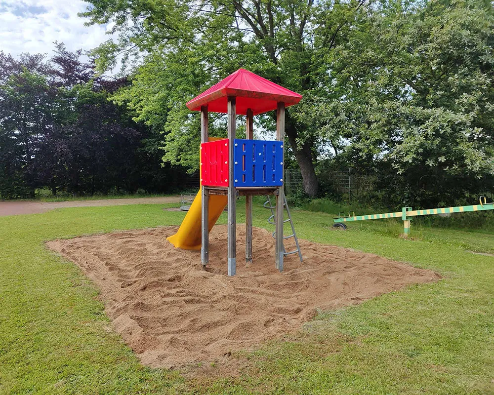 Ein Spielplatz mit einer frisch gereinigten Sandfläche, bereit zum Spielen.